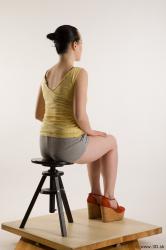 Sitting reference of whole body yellow t shirt gray shorts red shoes Hazel